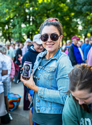 smiling woman holding can of key sparkling water